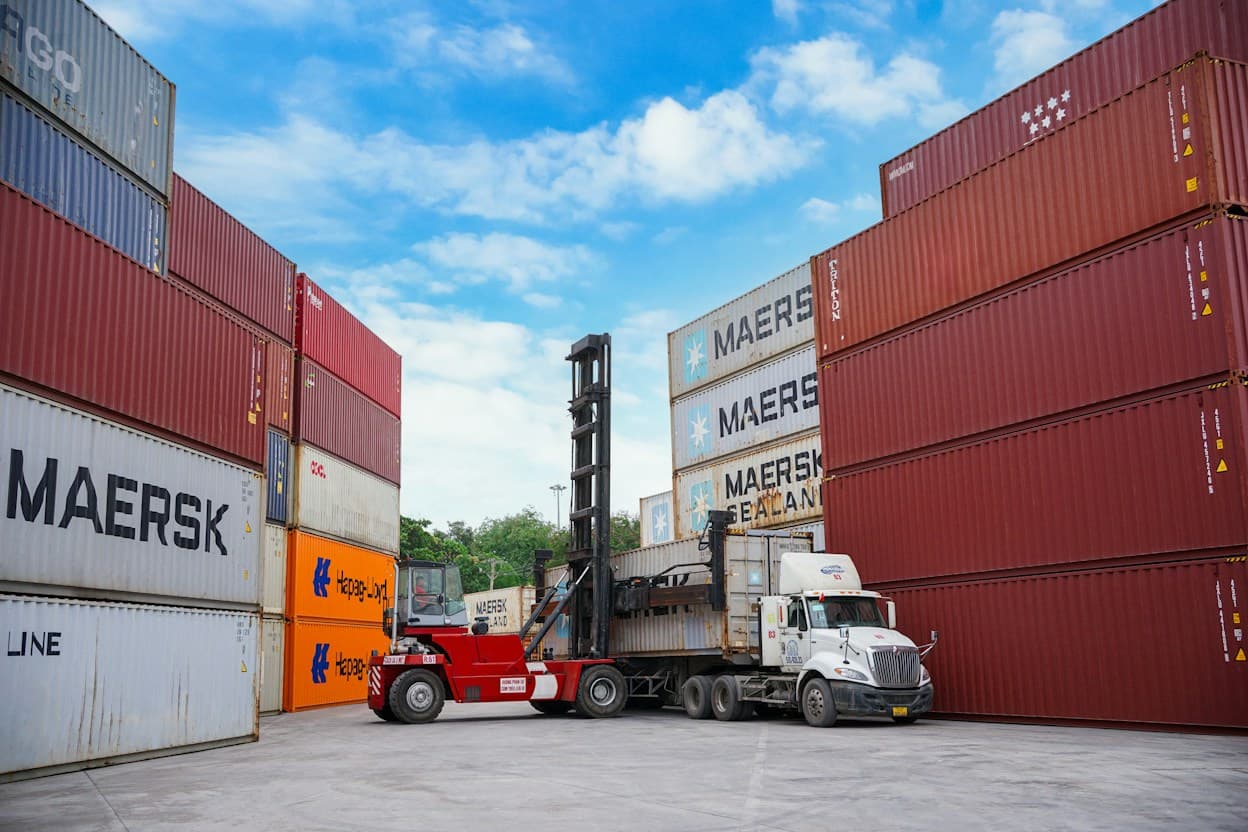 A reach stacker loading a container onto a truck at a port yard